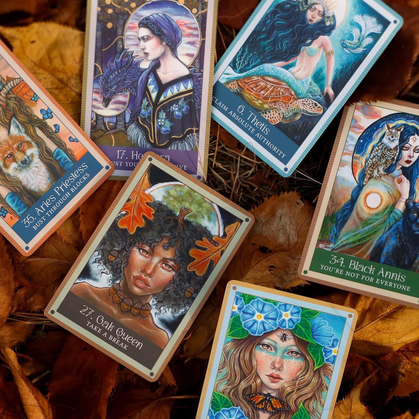 Collection of tarot cards with artistic illustrations on a leafy background