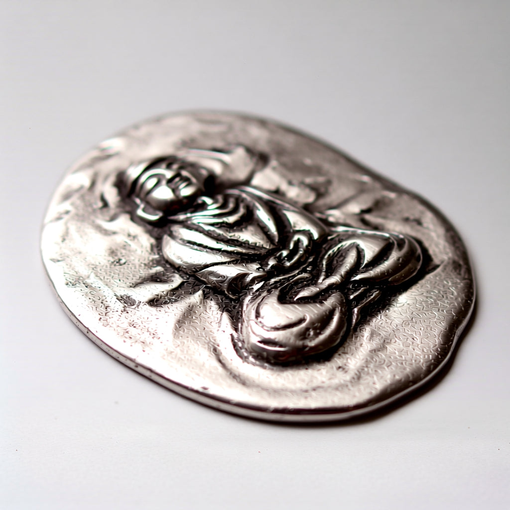 Silver pendant with a religious design on a light gray background