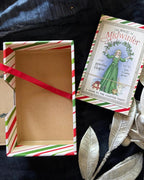 A vintage-style card deck box and its cover labeled 'The Magic of Midwinter' by Jennifer Higdon, styled on a dark fabric background with silver decorative leaves and a red ribbon.