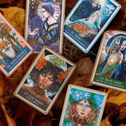 Collection of tarot cards with artistic illustrations on a leafy background