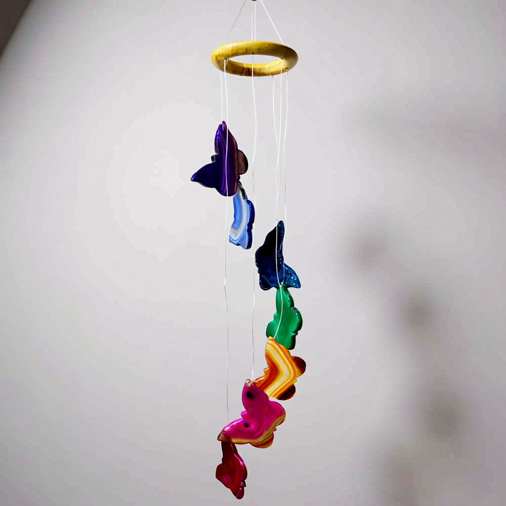 Colorful butterfly-shaped wind chime hanging against a plain background