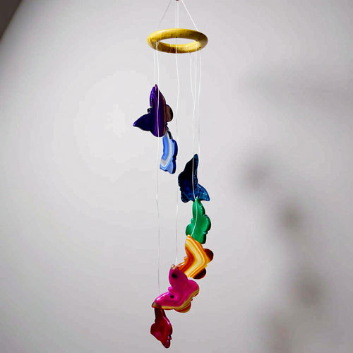 Colorful butterfly-shaped wind chime hanging against a plain background