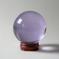 Purple crystal ball on a wooden stand against a gray background