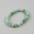 Beaded bracelet with green and beige beads on a gray background
