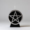 Candle with a pentagram design on a black base against a white background