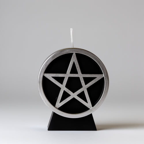Candle with a pentagram design on a black base against a white background