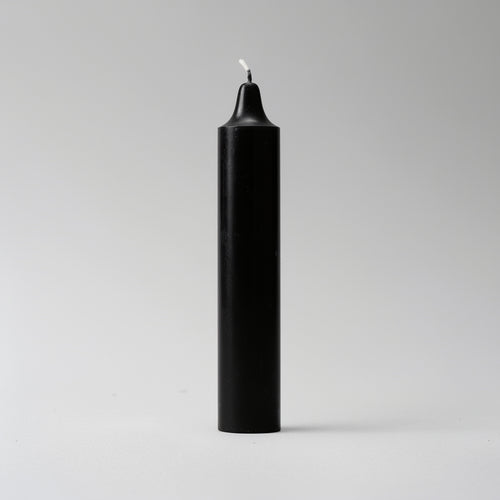 Black candle with a white wick on a light gray background