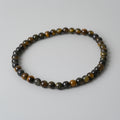 Beaded bracelet with brown and black stones on a light gray background