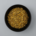 Black bowl filled with dried yellow flowers on a gray background