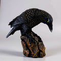 Black bird figurine on a rock against a white background