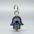 Silver Hamsa hand charm with a blue eye on a light gray background