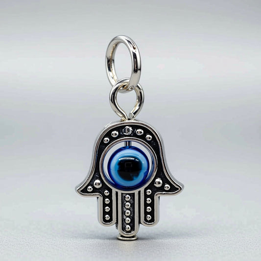 Silver Hamsa hand charm with a blue eye on a light gray background