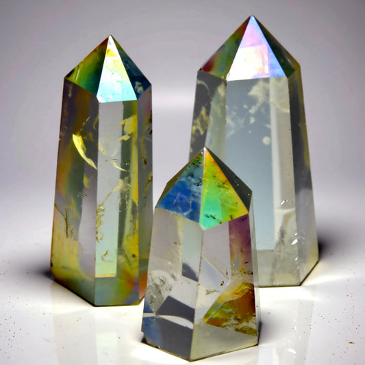 Three crystal prisms with multicolored facets on a neutral background
