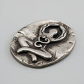 Silver decorative item with abstract design on a gray background