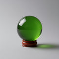 Green crystal ball on a wooden stand against a gray background