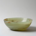 Green onyx bowl with brown swirls on a white background