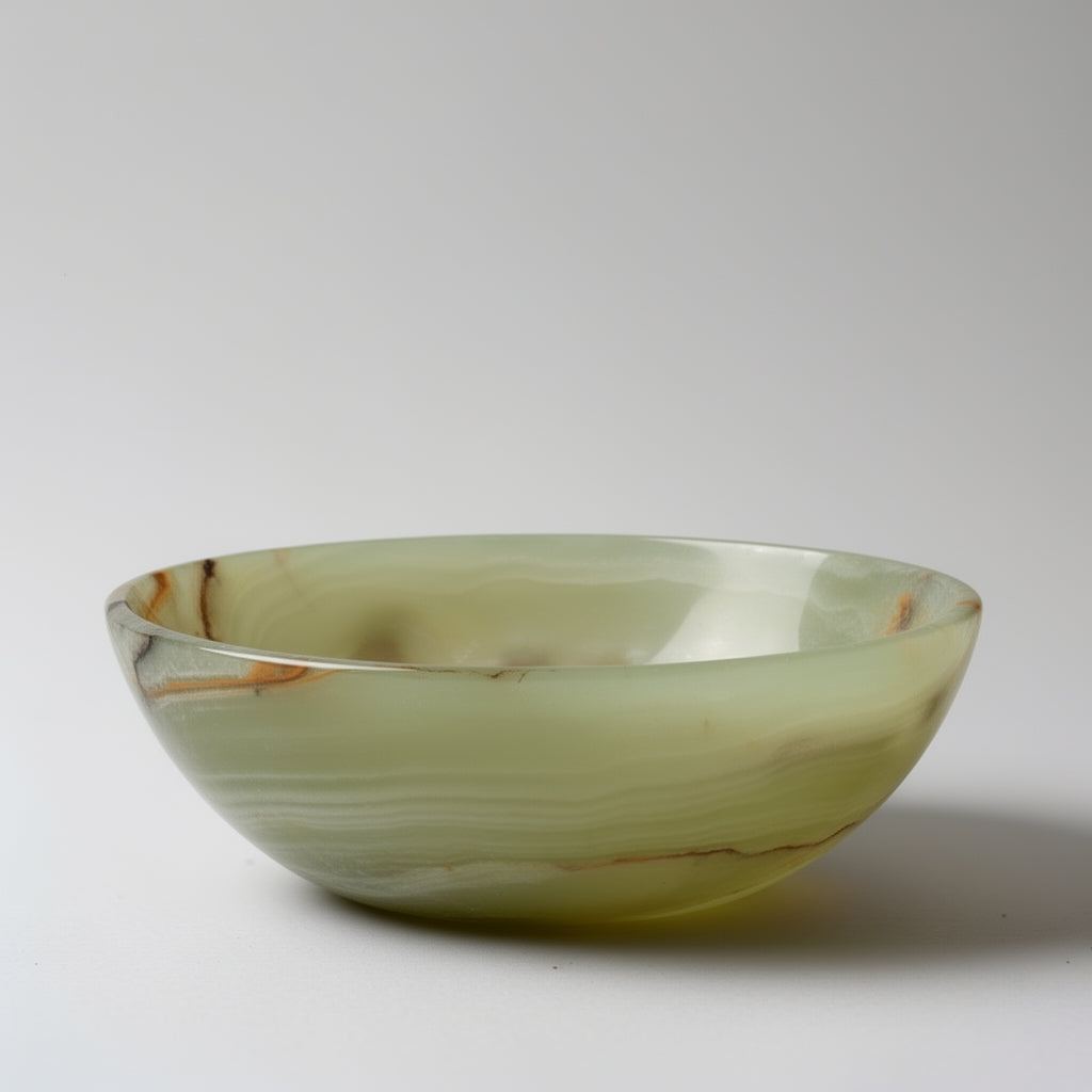 Green onyx bowl with brown swirls on a white background