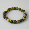 Beaded bracelet with green stones on a gray background