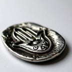 Pocket stone with Hamsa hand design on a light gray background