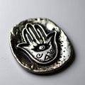 Pocket stone with Hamsa hand design on a light gray background