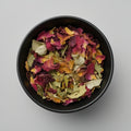 Black bowl filled with colorful dried leaves on a gray background