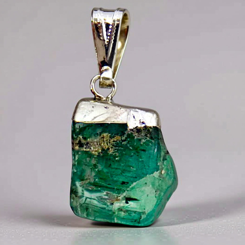 Green aquamarine gemstone pendant withsiler setting on a gray background