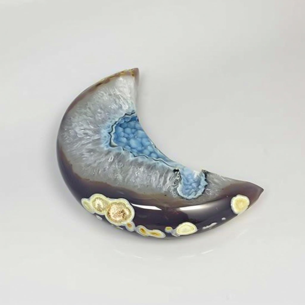 Crescent-shaped ceramic piece with blue and gold patterns on a white background