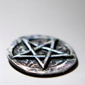 Pentagram pocket stone on a reflective surface with a blurred background