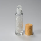 Clear glass roller bottle with wooden cap on a gray background