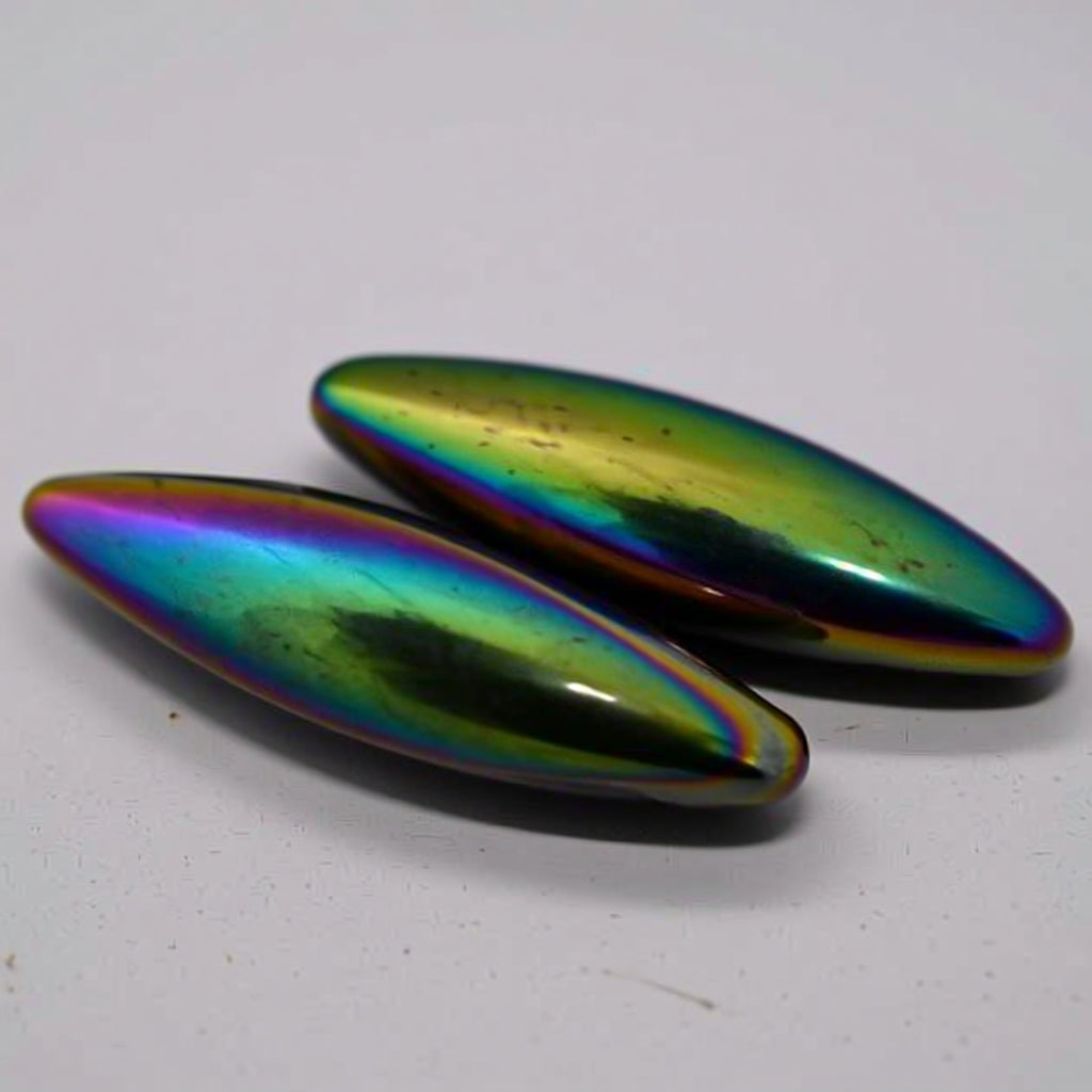 Two metallic, oval rainbow hematites on a white background