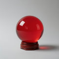 Red glass sphere on a wooden stand against a gray background