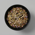 Black bowl filled with dried herbs on a gray background
