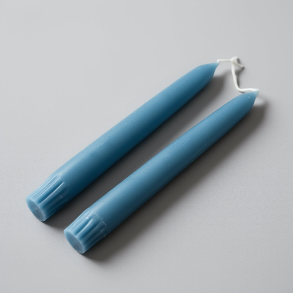Two teal taper candles on a gray background