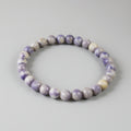 Purple and white beaded bracelet on a gray background