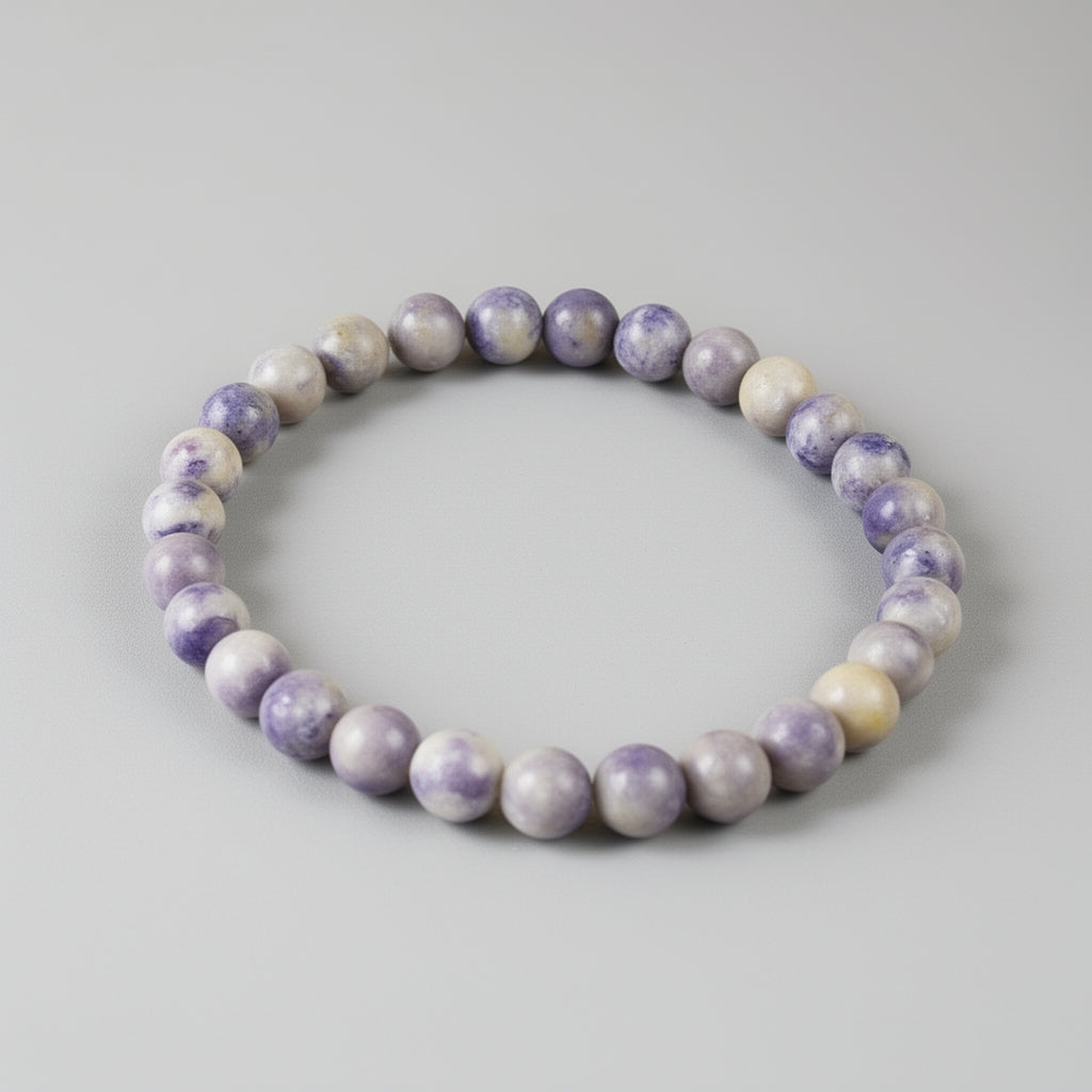 Purple and white beaded bracelet on a gray background