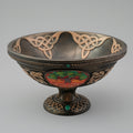 Decorative bowl with Celtic knot designs and a tree of life emblem on a gray background