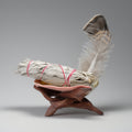 Bundled sage with a feather on a wooden stand against a gray background