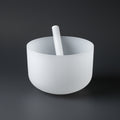 White bowl with a white sounding mallet on a dark gray background