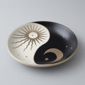 Ceramic plate with yin yang design featuring sun and moon on a gray background